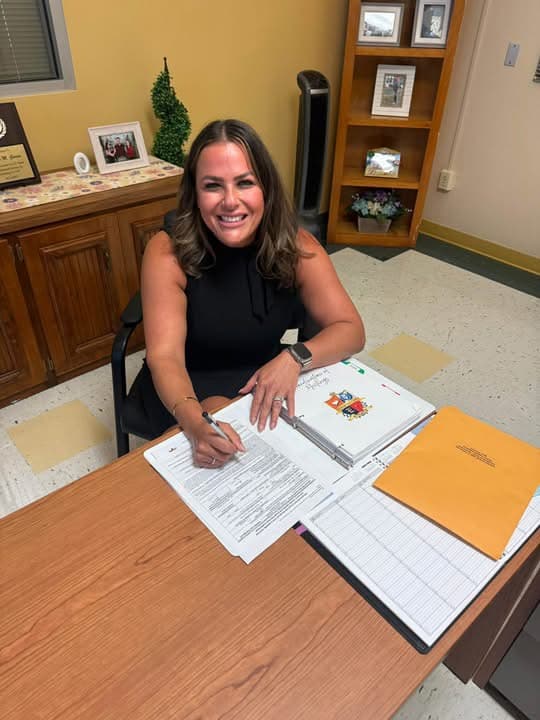 Dr. Karla signing official paperwork at a desk